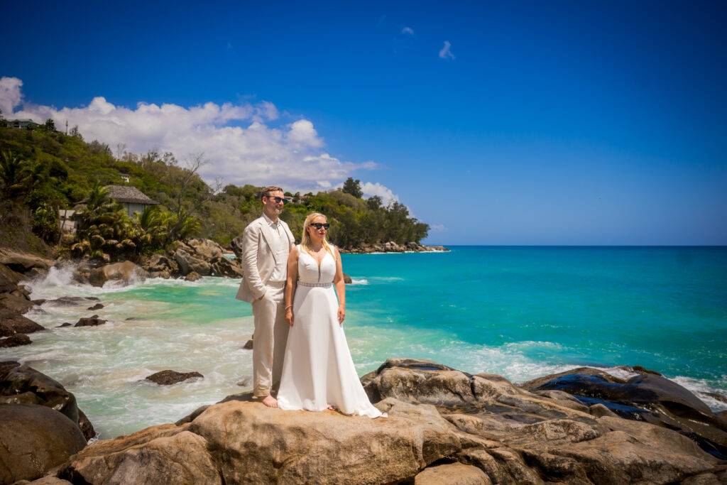 Brautpaar auf Granitfelsen vor türkisfarbenem Meer auf den Seychellen – Hochzeitsfotograf Seychellen